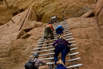 Climbing Anasazi Ruins - a group of tourists climbs a ladder to an upper floor of Anasazi cliff...