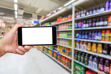 Fototapeta na wymiar Hand holding smartphone with white blank screen and blurred supermarket drink background
