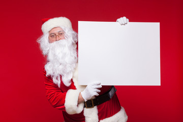 Santa Claus pointing in blank advertisement banner isolated on red background with copy space