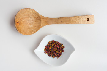 Sichuan red peppercorn with wood spoon on a white table