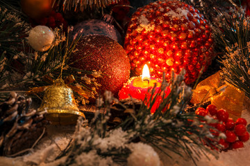 Fototapeta na wymiar red Christmas candle on the background of New Year's decorations and a bell. The magic of Christmas and New Year