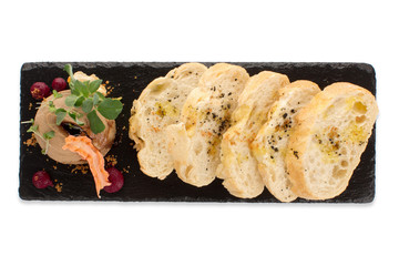 Studio shot of small board on slate plate with served slices of bread and pate Isolated