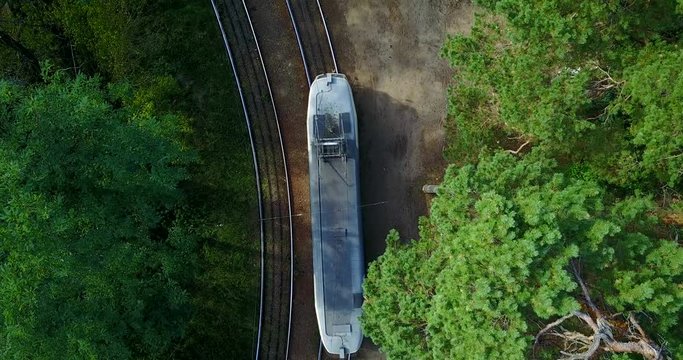 The tram goes on rails among the green forest. Interesting places in city Kiev. Vertical top view. Drone flight