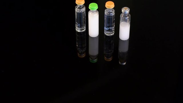 Four vials of insulin on a black background. Four ampoules for injection on a black background, close-up.