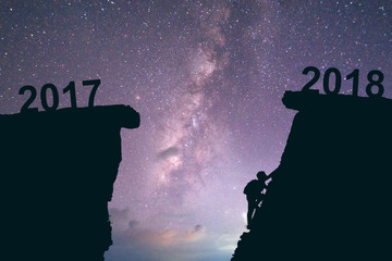 Young man climbing between 2017 and 2018 years. Happy new years 2018 concept Milky way background