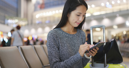 Woman looking at cellphone for time flight at Hong Kong airport