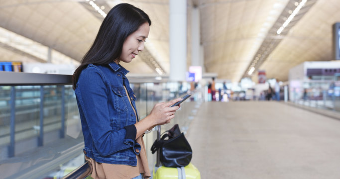 Woman sending sms on mobile phone in Hong Kong international airport