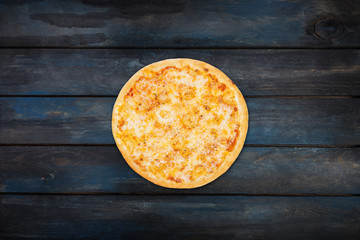 Perfect pizza margarita on a dark wooden background. Top view center orientation