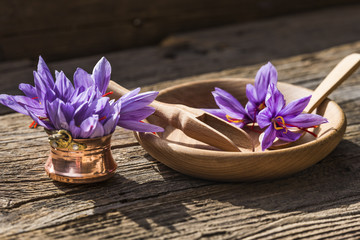 Saffron flowers in wooden bowl and saffron flowers bouquet illuminated by the afternoon sun
