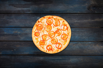 Perfect pizza margarita with tomato slices on a dark wooden background. Top view center orientation