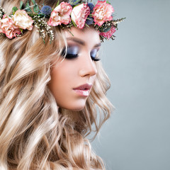 Beautiful Woman with Summer Pink Flowers. Blonde Beauty. Long Permed Curly Hair and Fashion Makeup