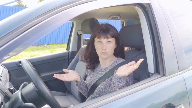 Young angry woman in perplexity sitting in the car.Slow Motion.