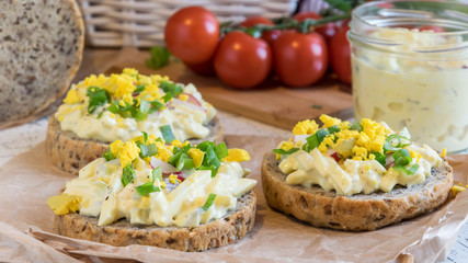 egg spread on round fresh homemade bread, decorated with spring onion and crushed yolk