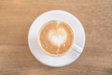 Hot coffee with beautiful art foam. Cup of latte art on wooden table