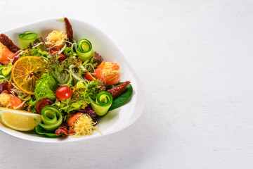 Salad with salted salmon, cheese and salad leaves. On a wooden surface. Top view. Free space for your text.
