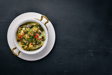 Baked vegetables with mushrooms and cheese. On a wooden surface. Top view. Free space for your text.