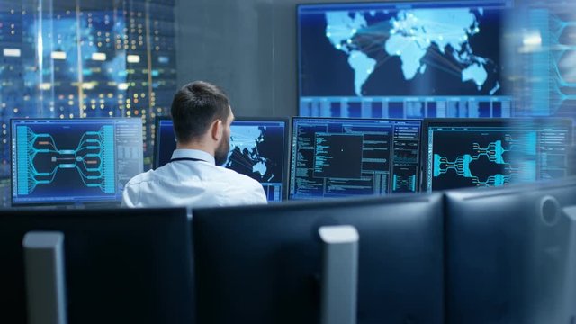 Back View in the System Control Center Operator Working. Multiple Screens Showing Technical Data. Shot on RED EPIC-W 8K Helium Cinema Camera.