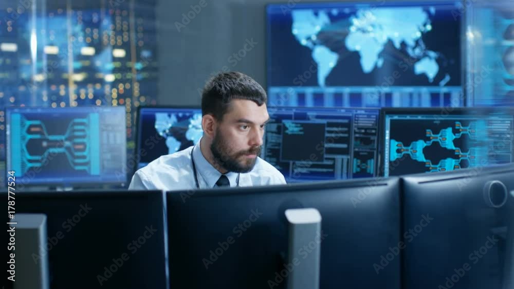 Leinwandbilder In the Monitoring Room Technical Operator Attentively Monitors Stability of the System. He's Surrounded By Screens Showing Technical Data. Shot on RED EPIC-W 8K Helium Cinema Camera.
