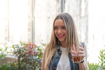 Happy young girl drinking a cocktail outdoor, during a sunny summer day. Photo taken in Milan, Italy