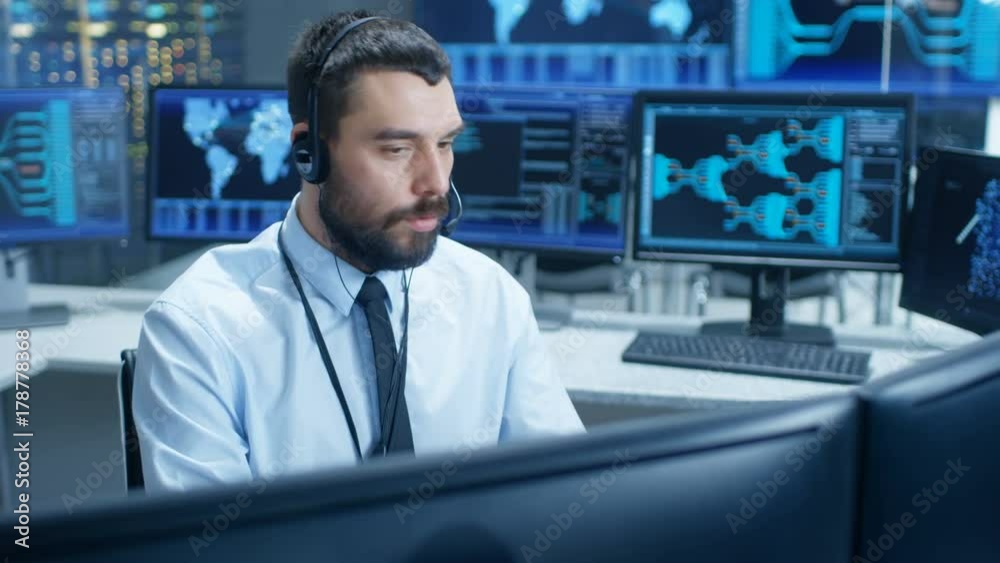 Poster In the System Monitoring Room Dispatcher Speaks into Headset, Observers Proper Functioning of the Facility. He's Surrounded by Screen Showing Technical Data. 