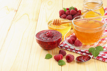 healthy background. raspberry with raspberry jam, honey and tea on light wooden background