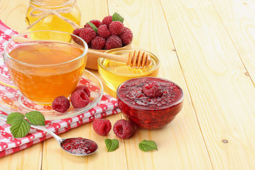 healthy background. raspberry with raspberry jam, honey and tea on light wooden background