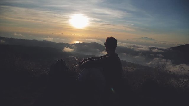 Man watching the sunrise from mount Batur, Bali - Indonesia.
