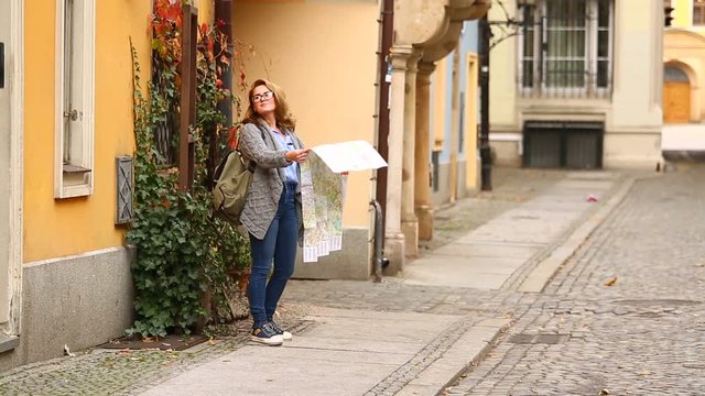 Woman traveler with a map looking for a building in a European city