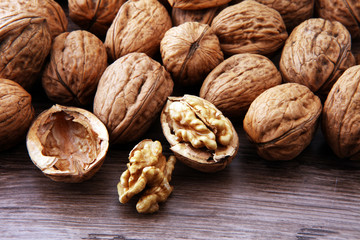 Walnut kernels and whole walnuts on brown wooden table.