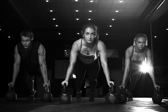 Muscular athletes exercising with kettlebells