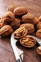 Walnut kernels and whole walnuts on brown wooden table.
