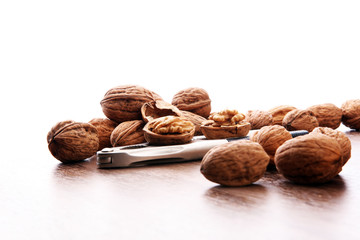 Walnut kernels and whole walnuts on brown wooden table.
