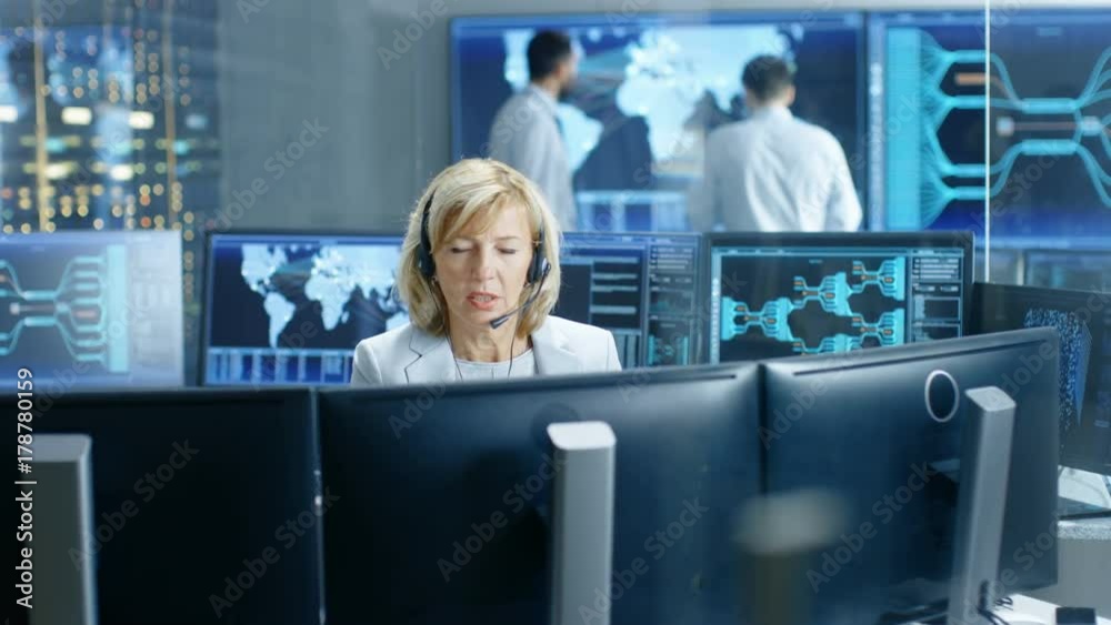 Poster System Monitoring Room Female Dispatcher Control Correct Functioning of the System. In the Background People Working with Interactive Map. Shot on RED EPIC-W 8K Helium Cinema Camera.