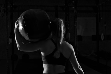 Fototapeta na wymiar Muscular woman working out in gym with heavy ball