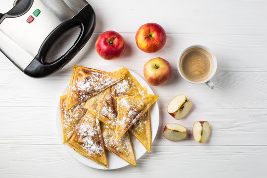 pies lie on the table next to apples, a toaster and a cup of coffee