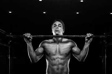 Young muscular man doing pull ups on bar