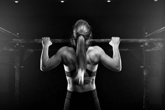 Young fitness female doing pull ups exercise