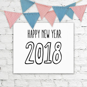 Happy new year 2018 on whiteboard hanging on white brick wall and part bunting flags background, new year greeting card