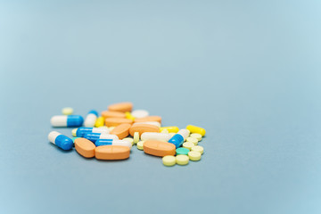 Heap of colorful pills on blue background, selective focus