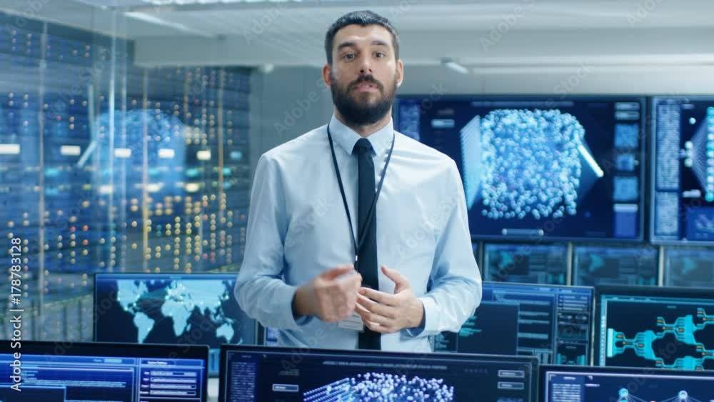Poster In the World's Top Machine Learning Facility Scientist Excitedly Describes Project He Works on. Background Shows Screens with Working Neural Network/ Artificial Intelligence. 