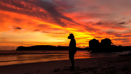 Fototapeta premium Silhouette a man is standing and watching sunset on beach.