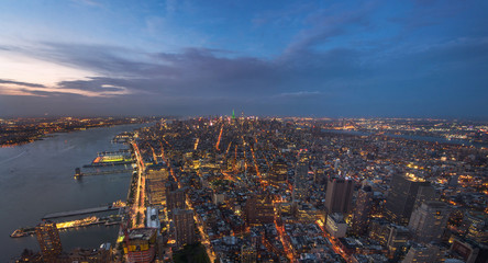 New York City Manhattan aerial panorama view at night with office building skyscrapers skyline illuminated by Hudson River.