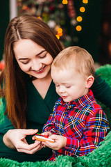 Mom has fun with her son sitting in the room dressed for Christmas and New Year