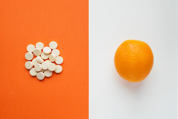 Vitamin C concept in minimalist style. Natural vitamin С in orange vs synthetic vitamin С in pills. Choice between natural and synthetic way of health care. Alternative medicine. Dietary supplement - obrazy, fototapety, plakaty