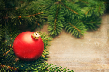 Red christmas ball and christmas fir tree on wooden background. Christmas background 