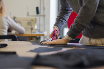 seamstress at work on the table, tailor woman work in studio with clothes 