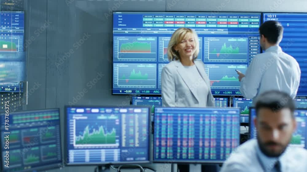 Poster Top Manager Enters Stock Market Operating Room Greeting Traders and Brokers. Room is Full of Monitor Showing Relevant Ticker Numbers and Graphs. Shot on RED EPIC-W 8K Helium Cinema Camera.