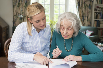 Woman Helping Senior Neighbor With Paperwork - obrazy, fototapety, plakaty