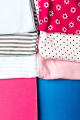 Fototapeta premium Fabric Sewing. Folded blue and pink bodysuit on minimalistic pink and blue background. diaper for newborn boy and girl. Stack of infant clothing. Child outfit. Top view