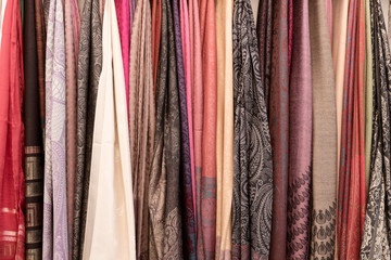 Many colorful scarves hanging for sale at market, colorful background